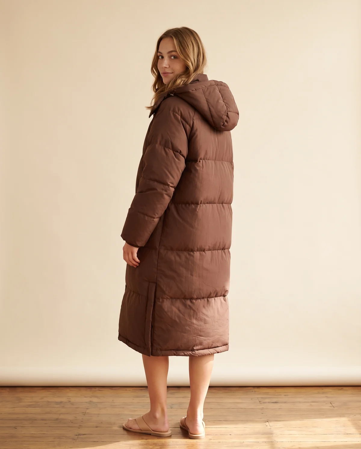 Long Hooded Puffer Coat in Chocolate, back view, worn by Ava