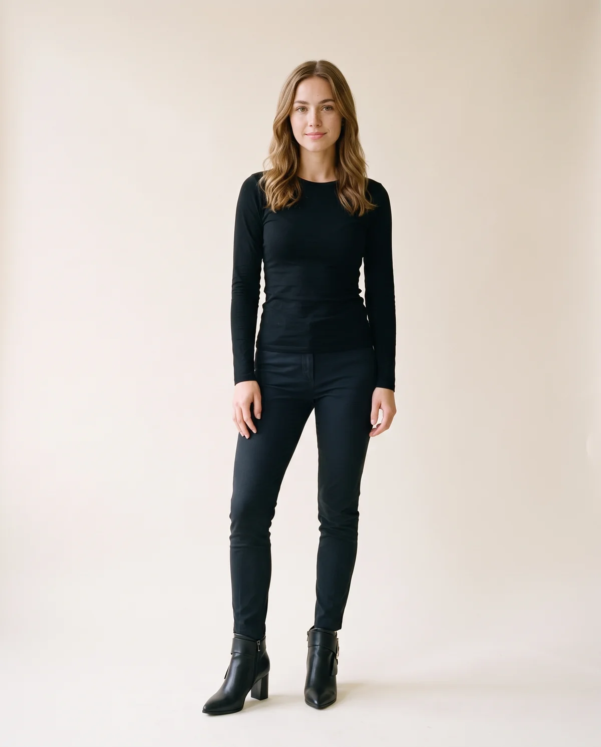 Buckle-Wrap Heeled Ankle Boot in Black, front view, worn by Ava